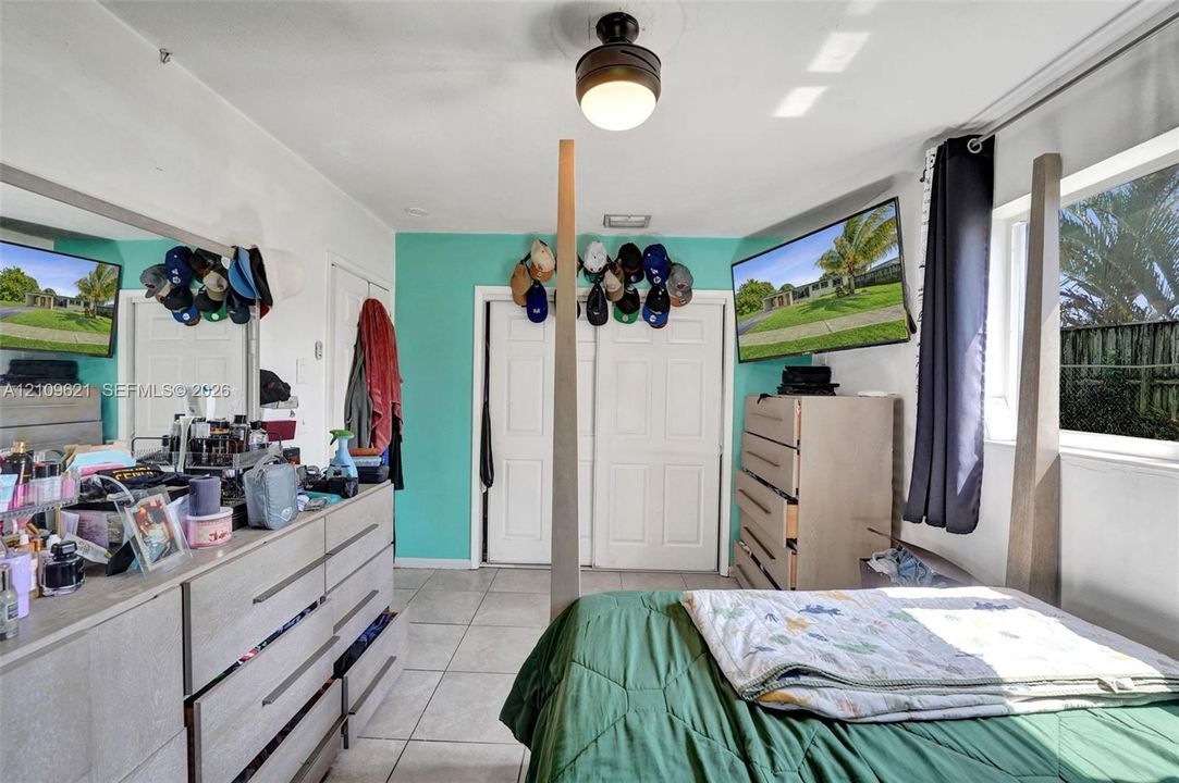 Ceramic tile flooring, double-door reach-in closet, and flush-mount ceiling fixture with integrated fan