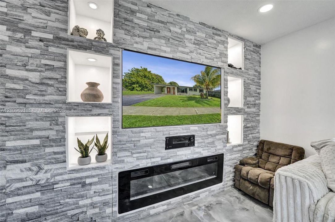 Floor-to-ceiling stone-veneer accent wall featuring five recessed display niches with integrated lighting and a built-in electric fireplace