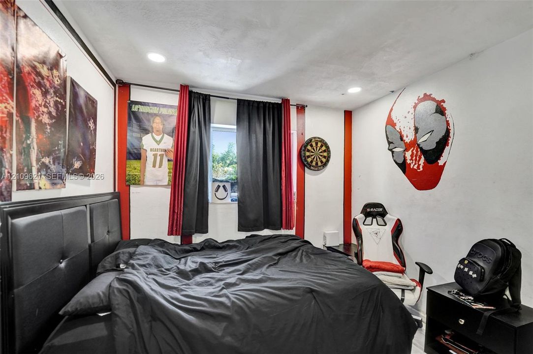 Bedroom featuring recessed ceiling lighting, red wall accents, and a window with neutral-toned walls