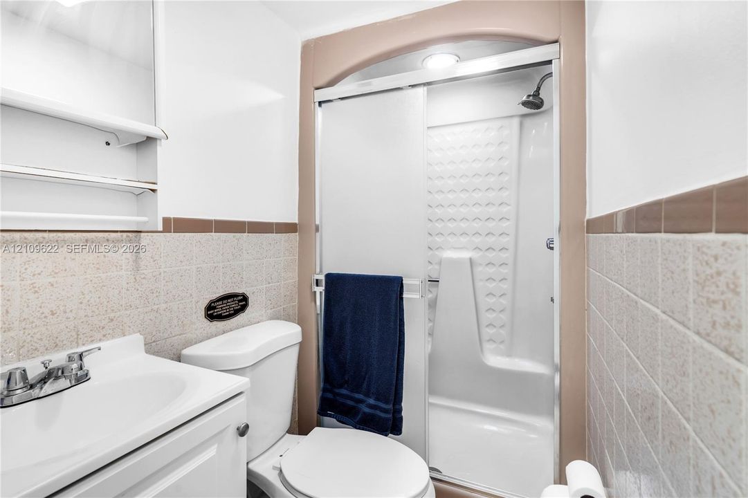 Bathroom featuring a walk-in shower with a glass sliding door, molded shower surround, recessed ceiling lighting, and a pedestal sink