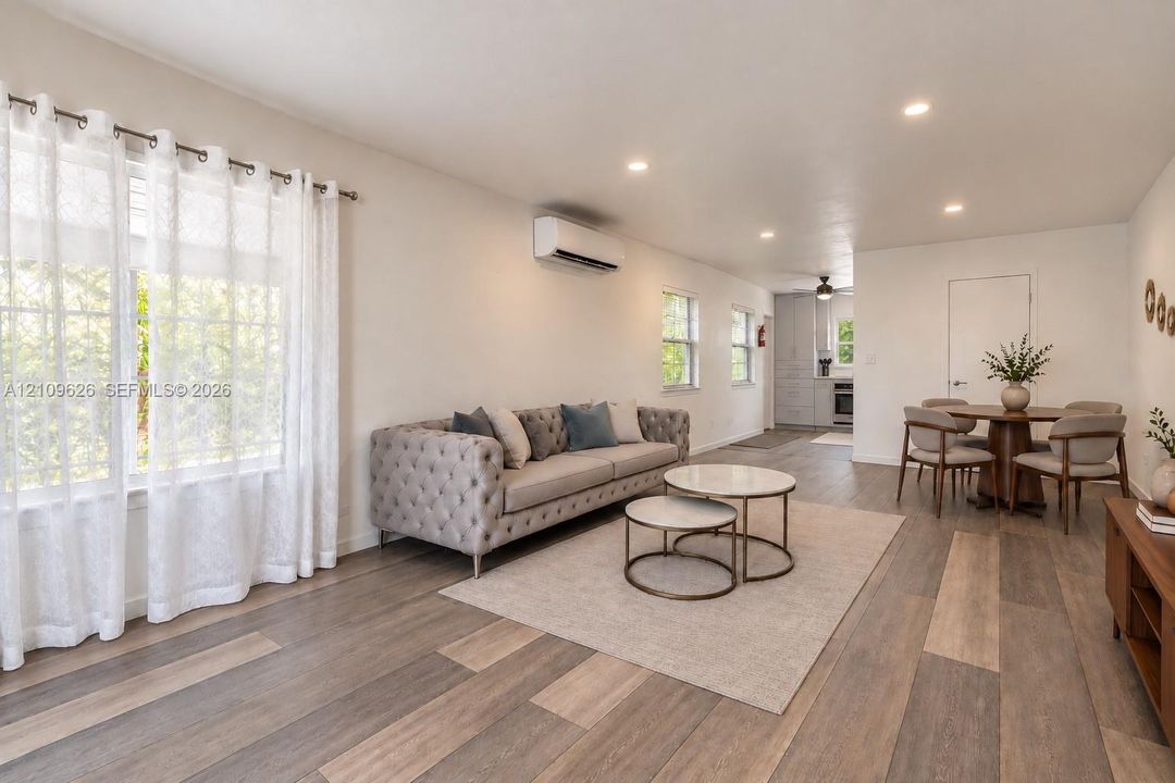 Open-concept interior featuring wood-finish flooring, recessed lighting, and a wall-mounted ductless HVAC unit