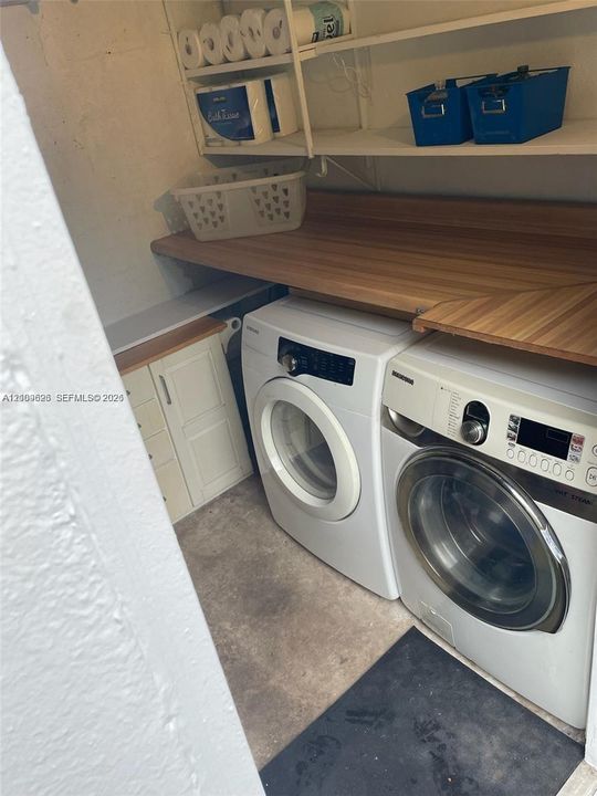 Laundry space featuring built-in wood-finish shelving, a wood-surface countertop, and lower cabinetry with integrated hardware