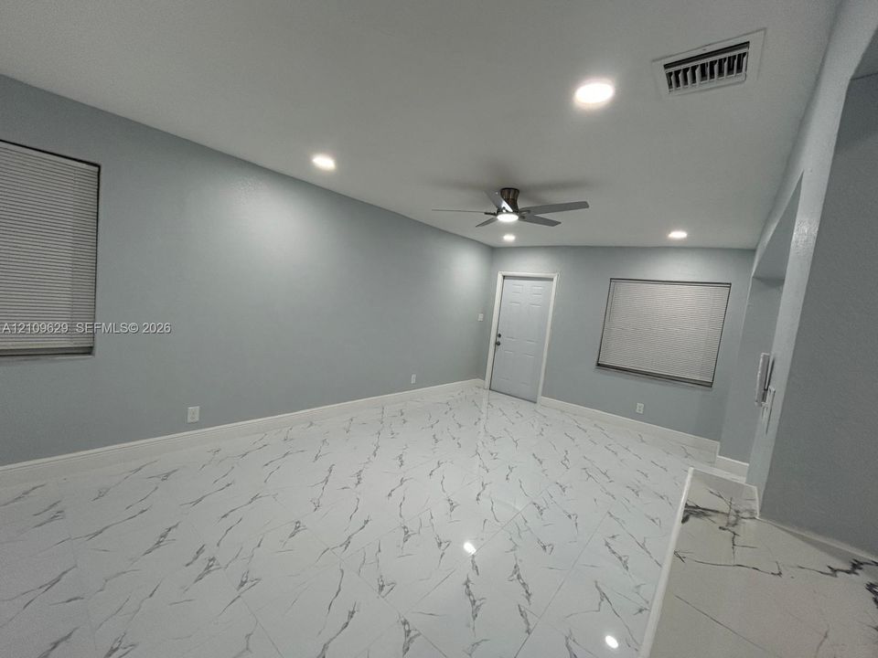 Large-format stone-patterned tile flooring, recessed ceiling lighting, and a multi-speed ceiling fan