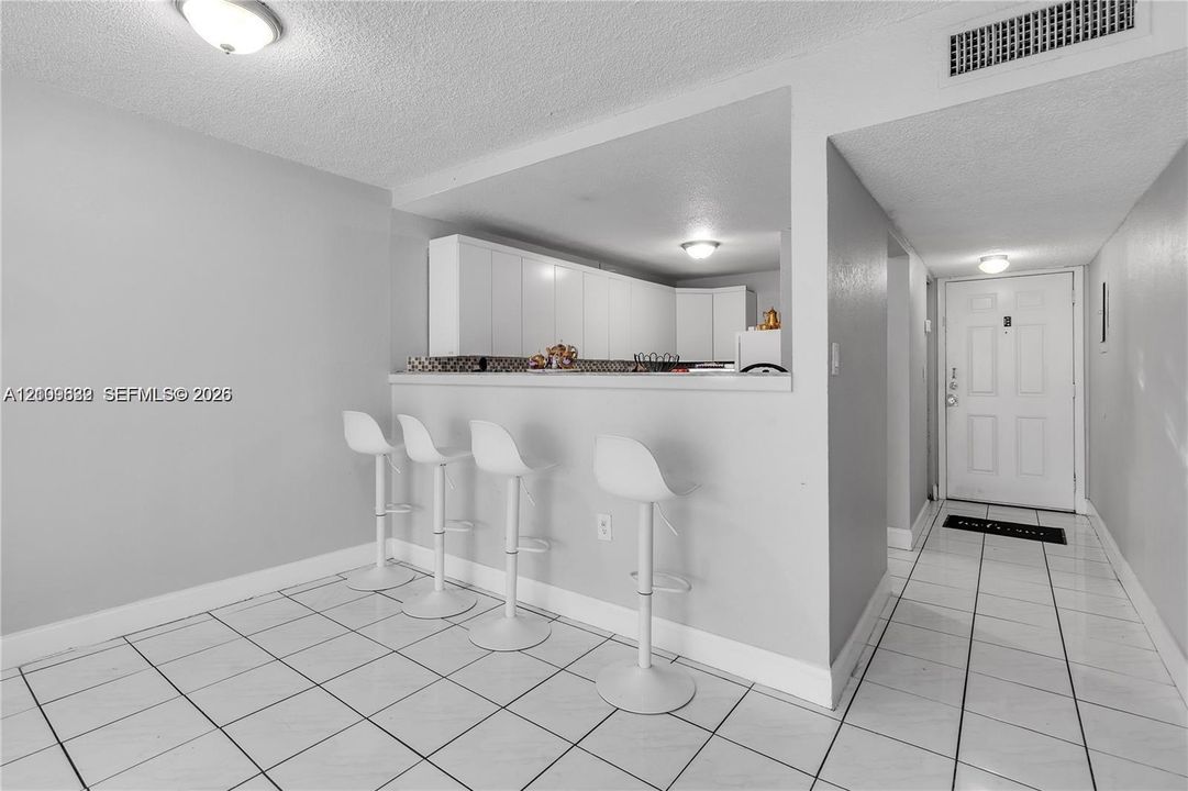 Kitchen featuring white cabinetry and a breakfast bar counter with tile flooring throughout