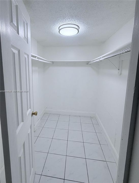 Walk-in storage space featuring ceramic tile flooring, built-in wire shelving, and a flush-mount ceiling light fixture
