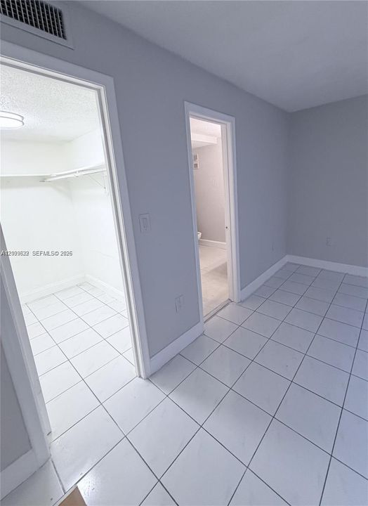 Neutral-toned interior featuring consistent ceramic tile flooring throughout, built-in shelving, and white door casings