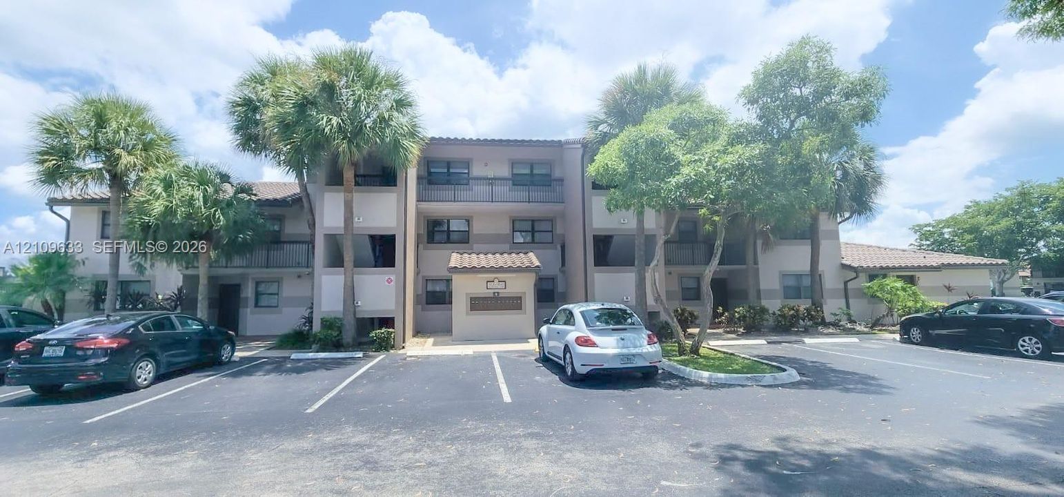 Multi-story exterior featuring a stucco facade, clay-tile roofline, covered entry portico, and attached private balconies