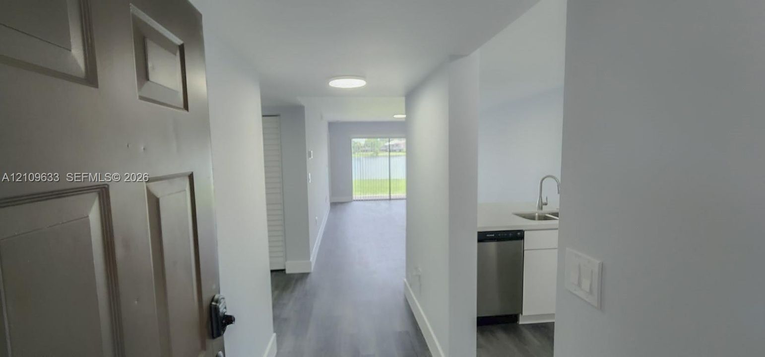 Entryway featuring wood-finish flooring, white walls, flush-mount lighting, and stainless steel kitchen appliances