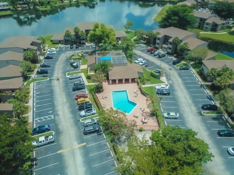 Community grounds featuring a swimming pool, paved sundeck, surface parking, and waterfront location