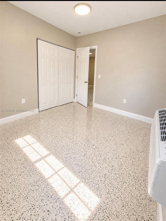 Polished terrazzo flooring, neutral wall tones, dual-panel closet doors, and a ceiling-mounted flush light fixture