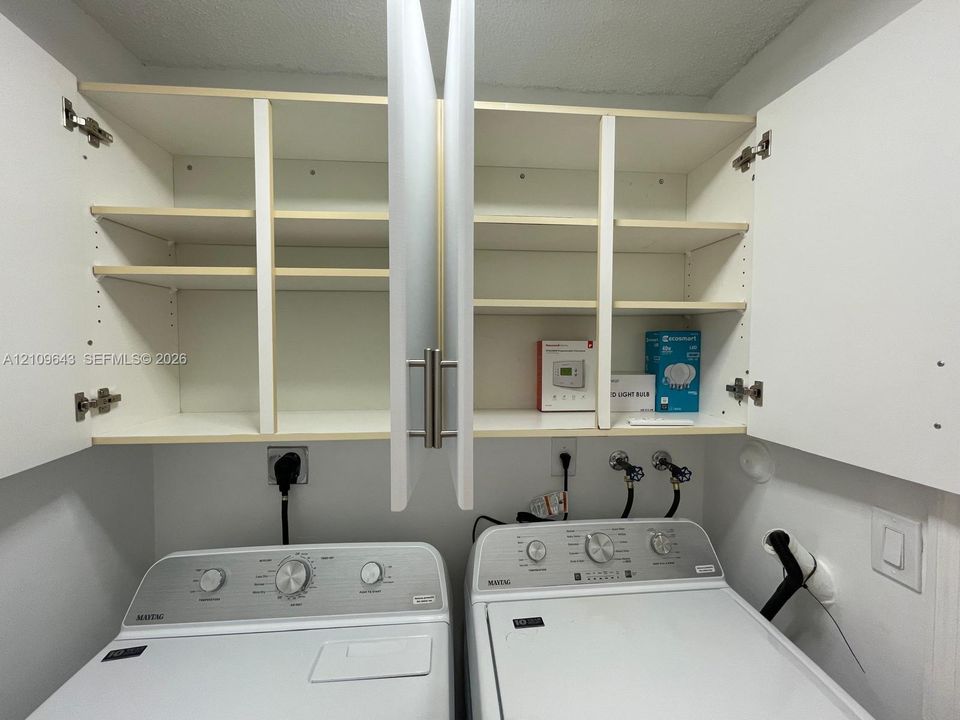 Wall-mounted white cabinetry featuring adjustable interior shelving and brushed metal bar pulls