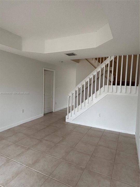 Ceramic tile flooring throughout with a staircase featuring a white wooden balustrade and handrail