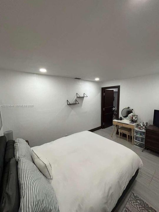 Recessed lighting, light-toned wood-finish flooring, and two wall-mounted matte black floating shelves