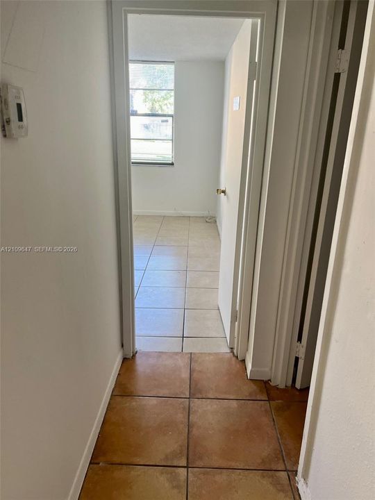 Interior hallway featuring ceramic tile flooring, neutral wall finishes, and a window providing natural light