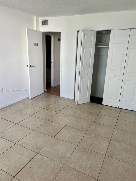 Neutral tile flooring, built-in dual-panel closet, and solid core interior doors