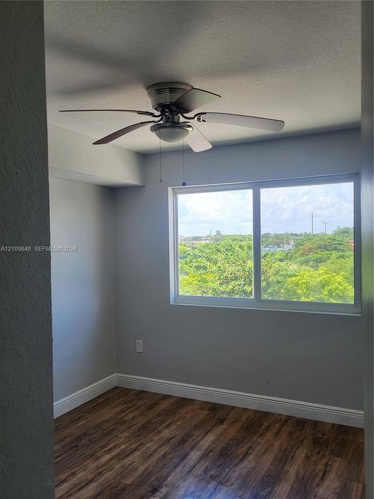 Wood-finish flooring, neutral wall tones, sliding window, and ceiling fan with integrated lighting