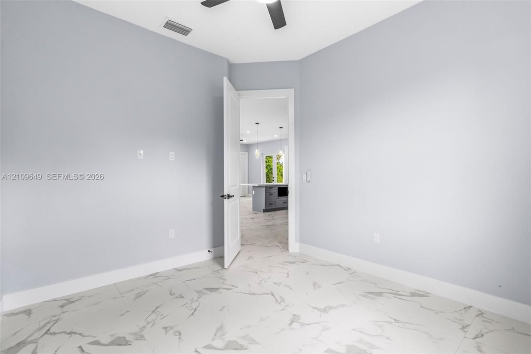 Room featuring large-format tile flooring with a veined pattern, neutral wall paint, and a ceiling-mounted fan