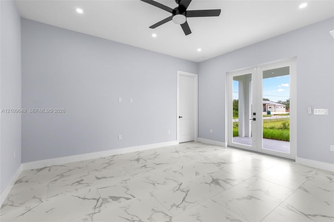 Large-format stone-patterned tile flooring, recessed ceiling lighting, matte black ceiling fan, and full-lite glass French doors