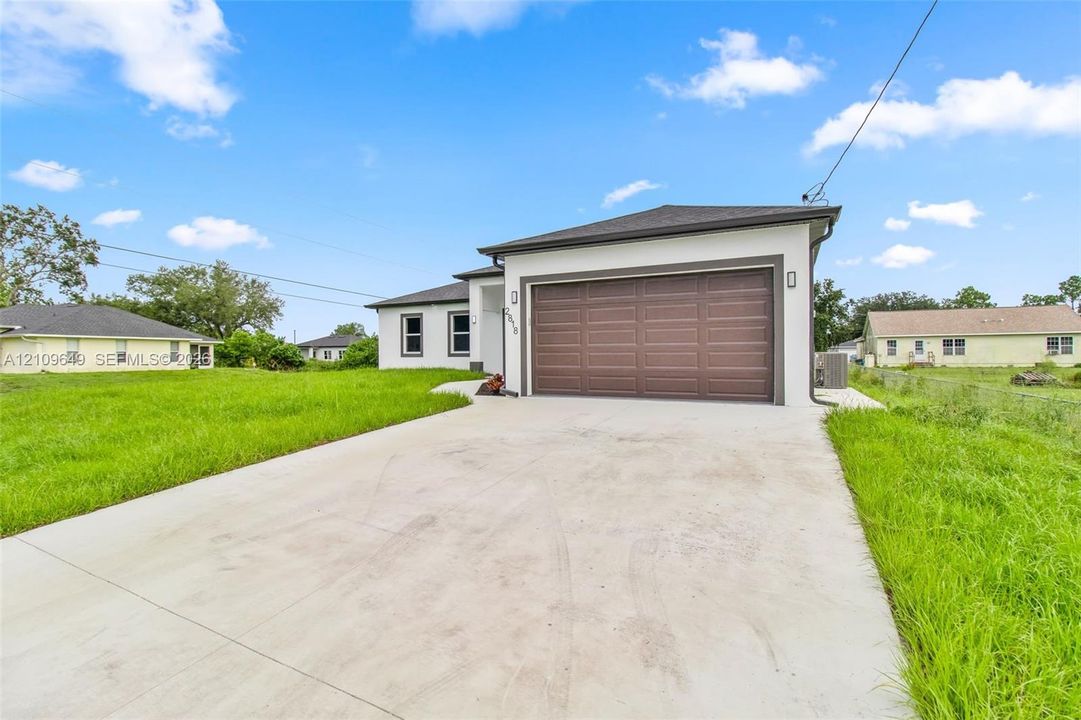 Single-story exterior featuring a stucco facade, concrete driveway, and attached two-car garage with a paneled door