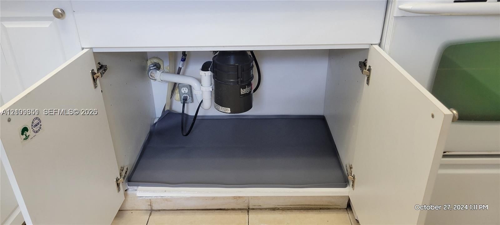 Cabinetry featuring white shaker-style doors, equipped with a heavy-duty garbage disposal and a protective floor mat