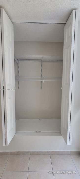 Storage closet featuring dual bifold doors and white wire shelving