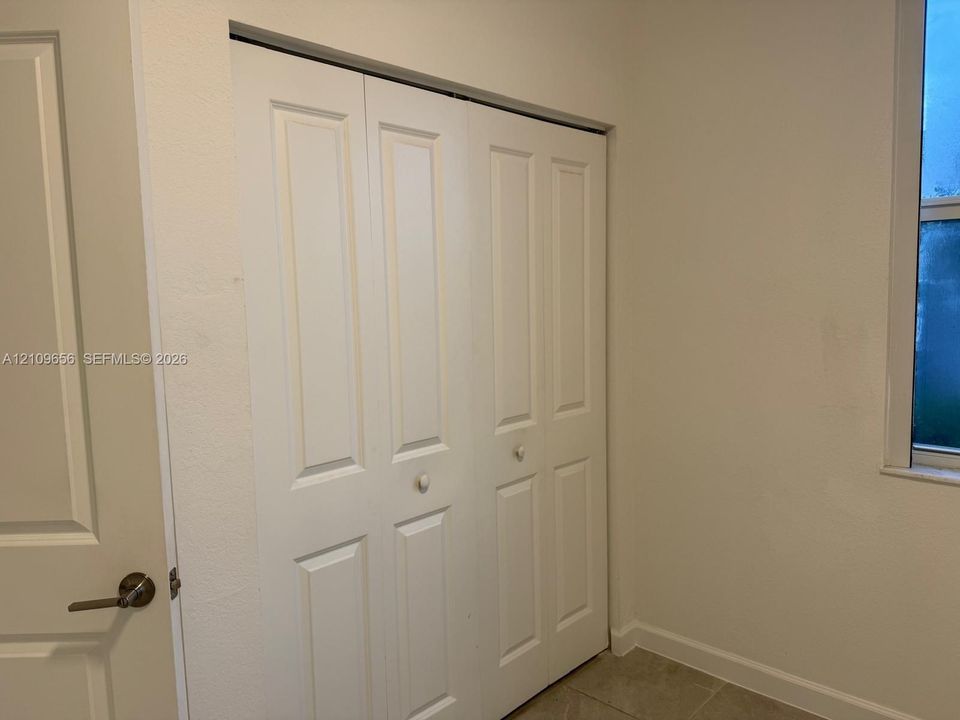 White bi-fold closet doors, interior door with brushed metal hardware, and neutral wall finish