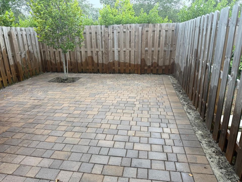 Private patio featuring modular stone pavers, a privacy wood-slat fence, and an integrated tree cutout