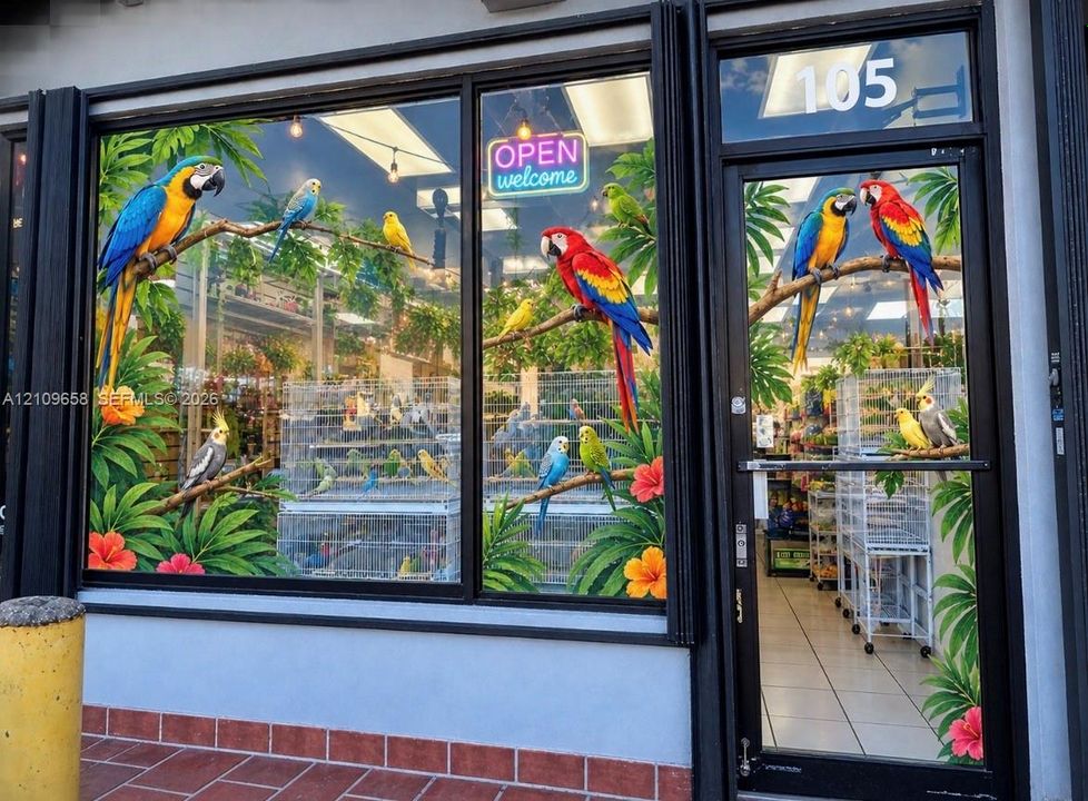 Commercial storefront featuring expansive floor-to-ceiling glass display windows, black-trimmed aluminum framing, and a full-height glass entry door with brick-style masonry base