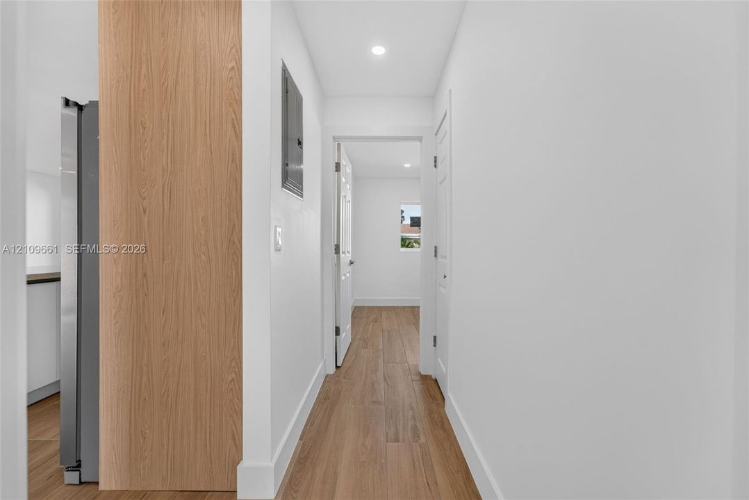 Hallway featuring wood-finish flooring, recessed lighting, and white paneled interior doors