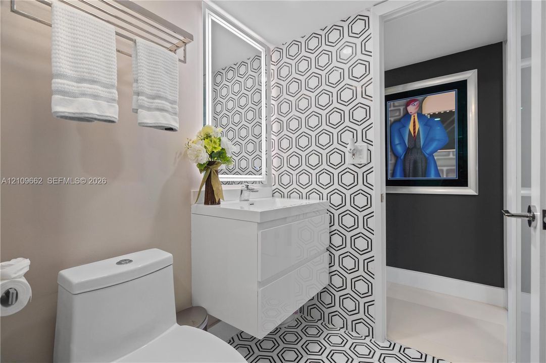 Modern floating vanity with integrated basin, geometric patterned tile feature wall and flooring, and LED-backlit mirror