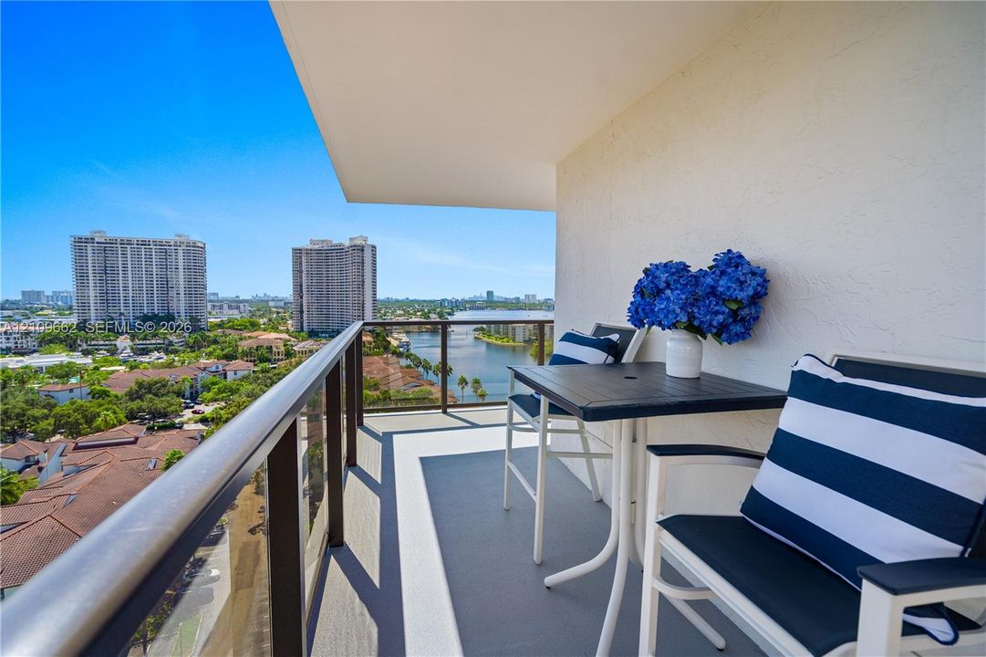 Covered balcony featuring glass-panel railings with a metallic handrail and concrete flooring