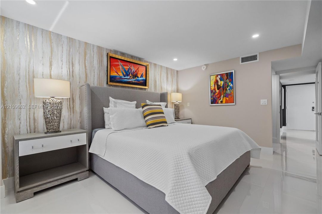 Bedroom featuring a textured metallic accent wall, high-gloss tile flooring, and recessed ceiling lighting