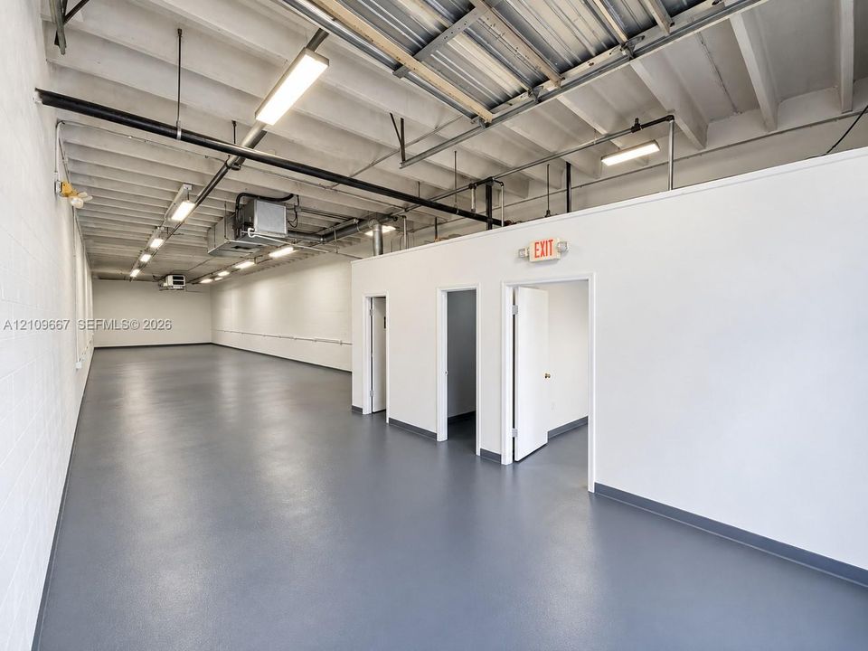 Expansive interior space featuring painted concrete block walls, high exposed-beam ceilings, and durable coated flooring