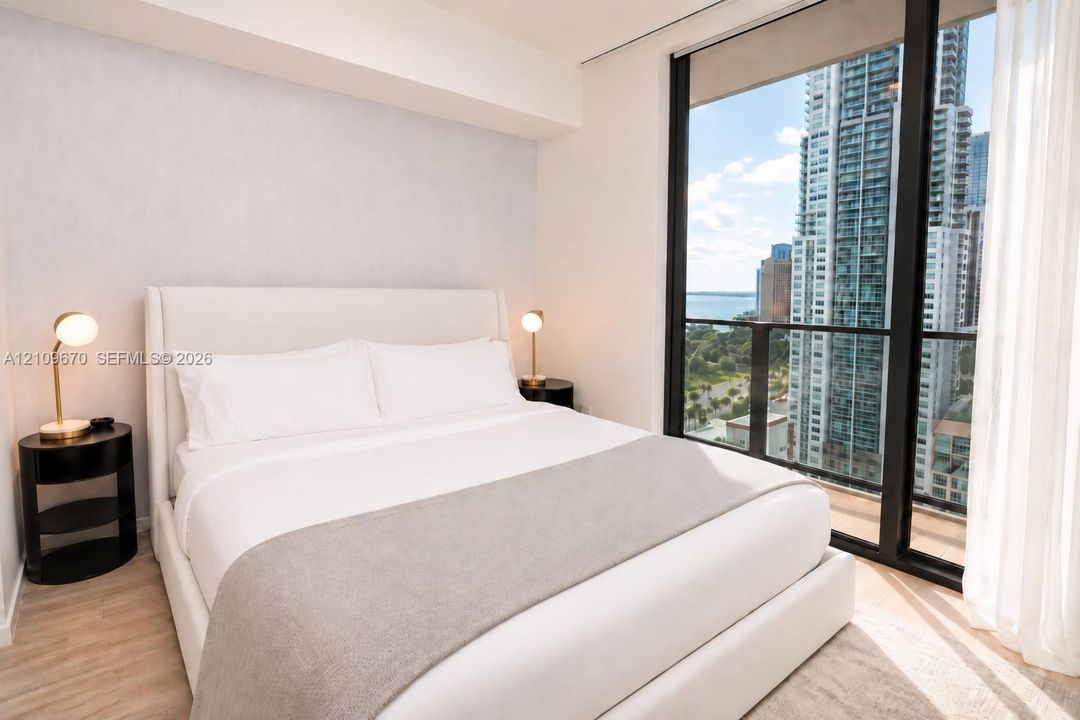 Floor-to-ceiling windows with expansive urban and water scenery, wood-finish flooring, and neutral wall tones