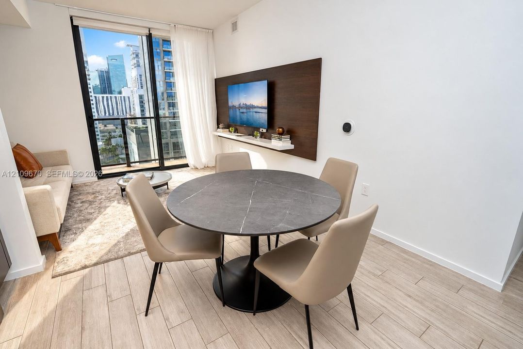 Floor-to-ceiling glass door, wood-finish tile flooring, and integrated wall-mounted media console