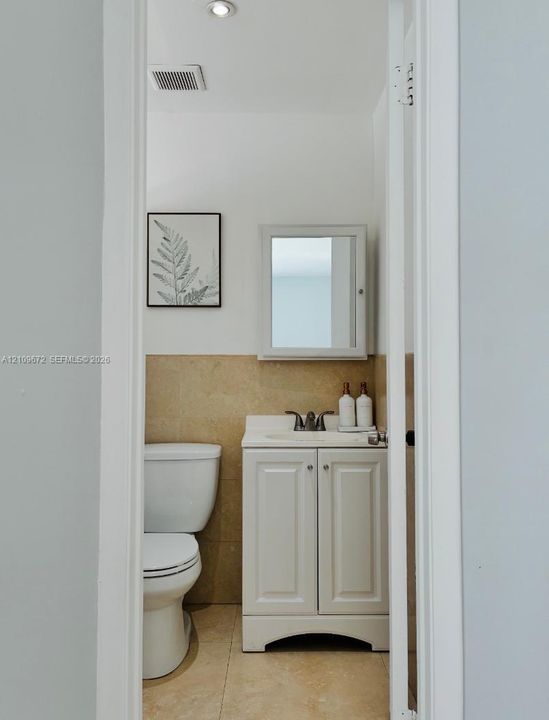 Shower area featuring floor-to-ceiling stone-look tiling, a rectangular rainfall shower head with a handheld sprayer, mosaic floor tiling, and a frosted glass window