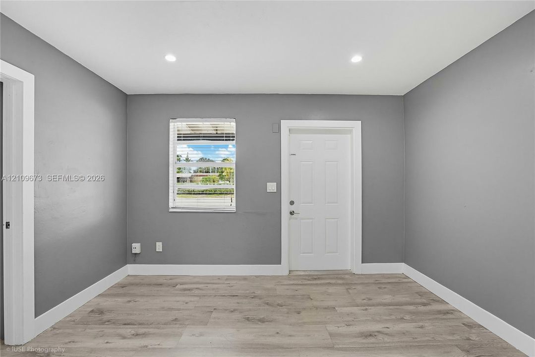 Interior space featuring wood-finish flooring, neutral gray walls, recessed lighting, and a six-panel door