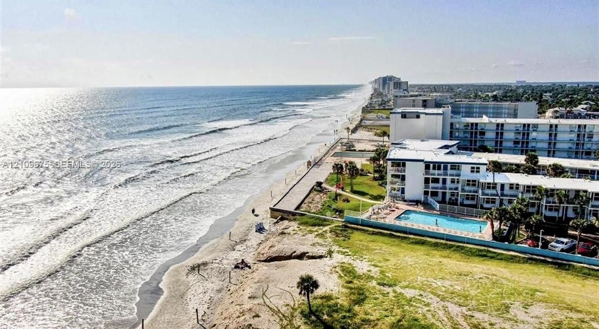 Oceanfront property featuring direct beach access, a paved boardwalk, and a swimming pool