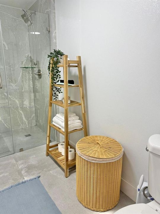Walk-in shower featuring large-format stone-finish tile, glass enclosure, and wall-mounted shower hardware