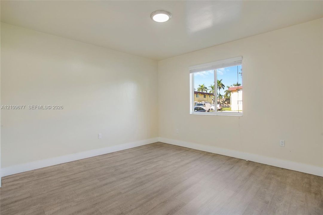 Neutral wall finishes, wood-finish flooring, and single-pane window with white roller shade