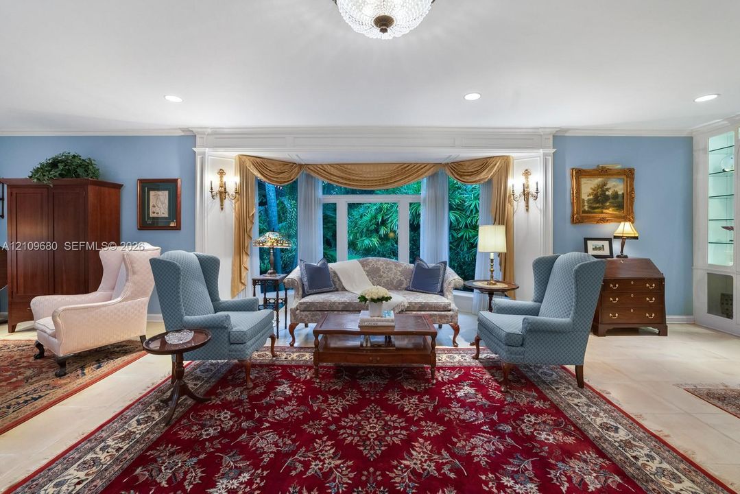 Large bay window featuring recessed lighting, custom wall-mounted sconces, light-toned tile flooring, and built-in glass-front cabinetry