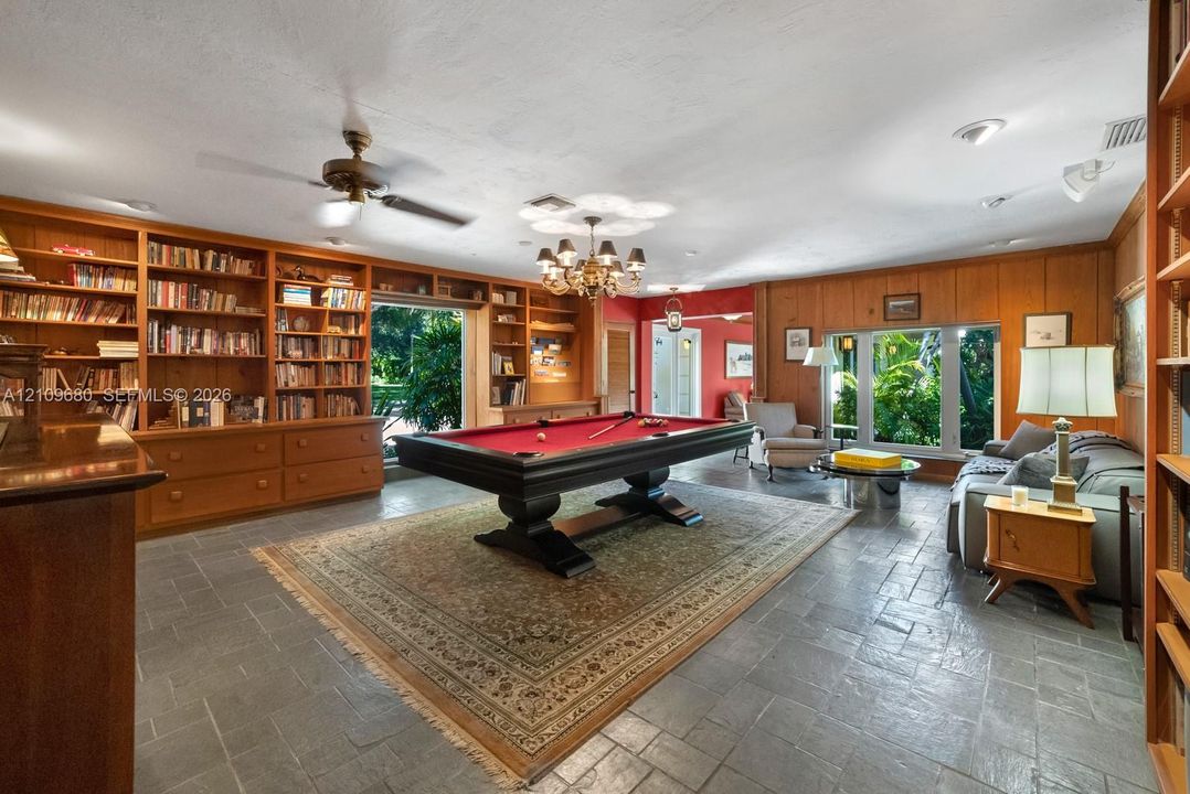 Expansive room featuring floor-to-ceiling wood-finish built-in cabinetry, stone tile flooring, a multi-arm chandelier, and large windows