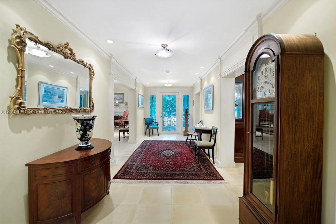 Foyer featuring light-toned tile flooring, crown molding, recessed ceiling lighting, and a glass-paneled entry door with decorative metal inserts