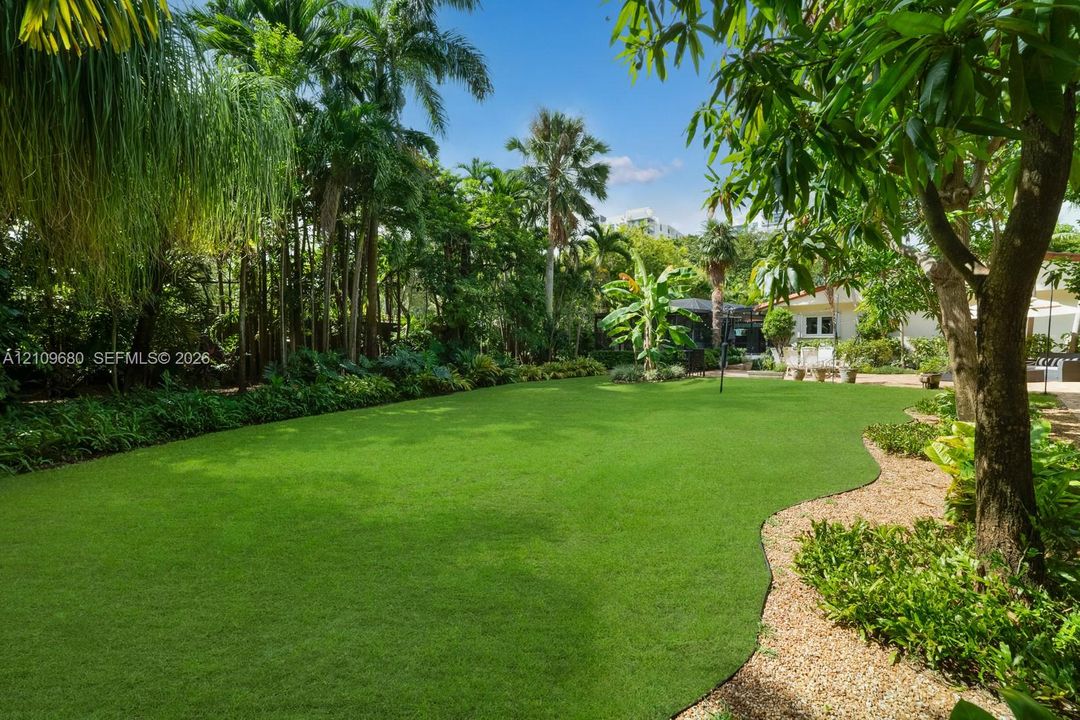 Expansive lawn area, mature tropical landscaping, and decorative gravel pathways