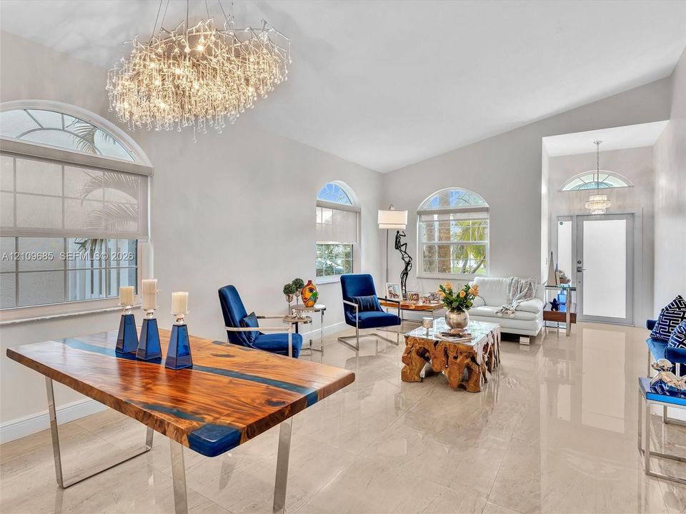 Polished stone tile flooring, vaulted ceilings, arched windows, and a multi-tiered crystal chandelier