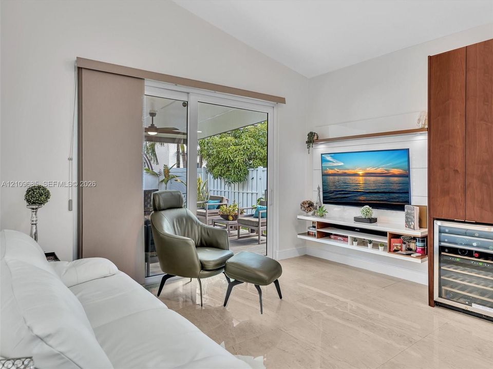 Vaulted ceilings, large-format tile flooring, built-in floating media console with integrated shelving, tall wood-finish cabinetry, and glass sliding doors