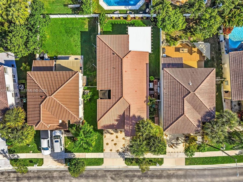 Aerial perspective of the property featuring a tile roof, covered patio, rear yard space, and concrete paver driveway
