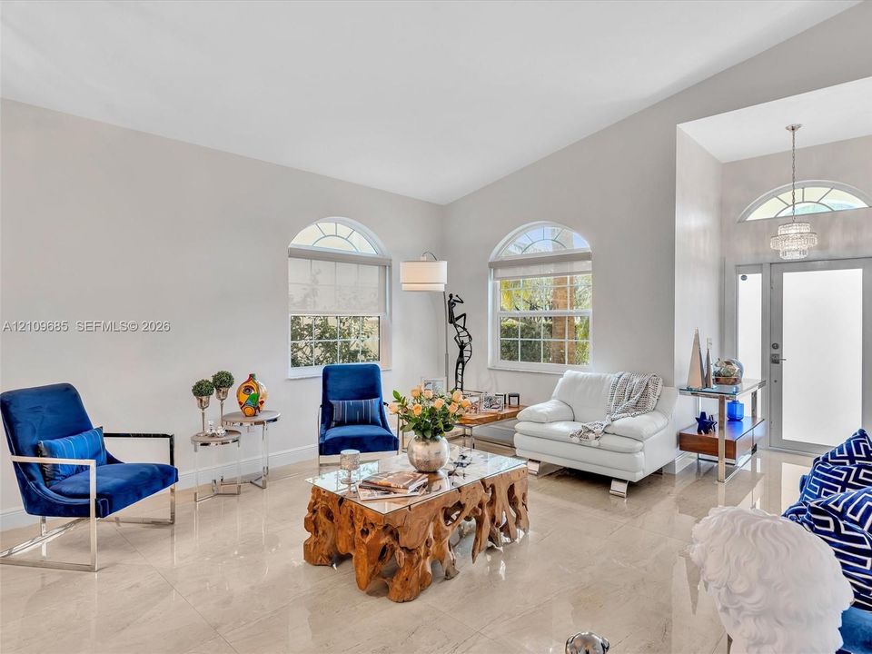 Vaulted ceilings, large stone-finish tile flooring, arched windows, and an arched entry door with a transom window