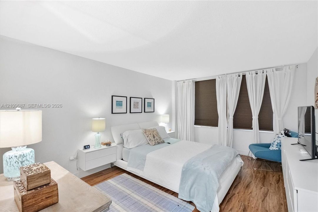 Wood-finish flooring, neutral wall tones, and large windows with integrated blinds