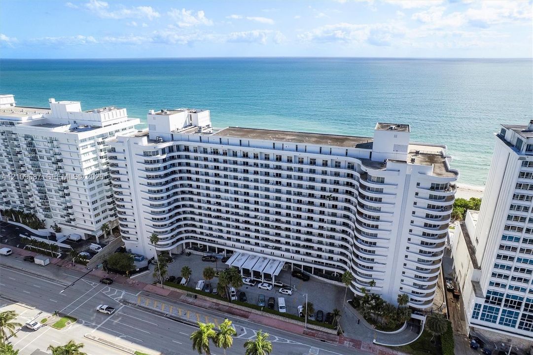 High-rise residential building featuring a curved architectural design, continuous private balconies, and a direct oceanfront location